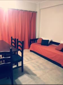 1 dormitorio con 2 camas, mesa y cortina roja en Azucena Apart en Salta