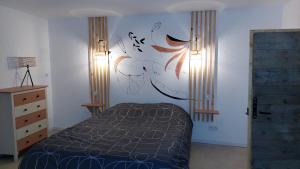 Schlafzimmer mit einem Bett mit Wandgemälde in der Unterkunft maison en pierre avec balnéo entre Toul et nancy 