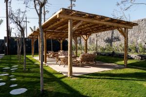 a wooden pavilion with tables and chairs in a yard at Cresanto Luxury Suites in Imerovigli