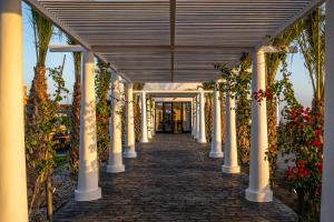 een loopbrug met zuilen en bloemen in een gebouw bij Cresanto Luxury Suites in Imerovígli