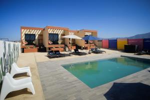 a pool on the roof of a building with chairs and umbrellas at Casas VV in Valle de Guadalupe