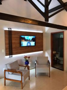 奧蘭布拉的住宿－Chalé no campo，客厅配有两把椅子和墙上的电视