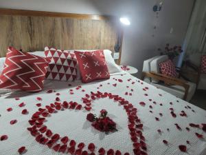 uma cama com um coração feito de rosas vermelhas em Chalé no campo em Holambra