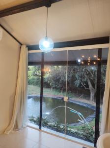 een raam in een kamer met uitzicht op een vijver bij Chalé no campo in Holambra