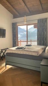 a bedroom with a bed and a large window at Kitzbüheler Alpenpenthouse *private Sauna&Whirlpool* by STELLENBERG living in Hollersbach im Pinzgau