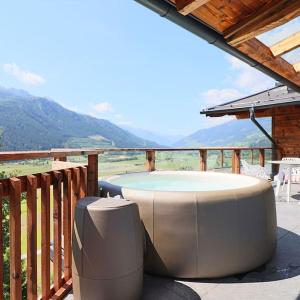 a patio with a hot tub and a table on a deck at Kitzbüheler Alpenpenthouse *private Sauna&Whirlpool* by STELLENBERG living in Hollersbach im Pinzgau