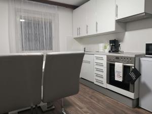 een keuken met witte kasten en een fornuis met oven bij Eisenerzer Apartmenthaus in Eisenerz