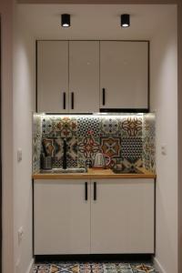 eine Küche mit weißen Schränken und Wandfliesen in der Unterkunft Blloku Studio Apartament in Tirana