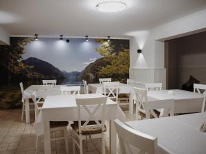 restauracja z białymi stołami i krzesłami oraz obrazem na ścianie w obiekcie Leśne Wzgórze Korbielów w Korbielowie
