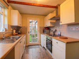 cocina con armarios blancos y suelo de madera en Wyndhead Cottage, en Lauder