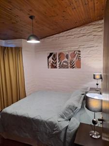 1 dormitorio con 1 cama y 1 mesa con lámpara en PORTAL ANDINO en Godoy Cruz
