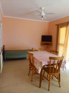 a dining room with a table and chairs and a tv at Los Palmares Del Urugua-i Bungalows in Colón