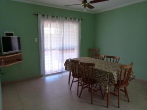 a dining room with a table and chairs and a television at Los Palmares Del Urugua-i Bungalows in Colón