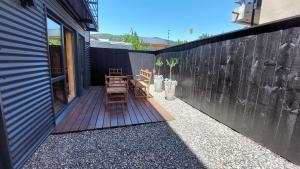 un patio con 2 sillas de madera y una valla en Hermoso departamento 2 ambientes con amplio jardin en el centro de SMA. 6V5 en San Martín de los Andes