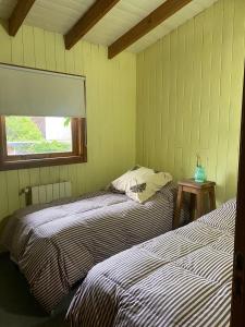 twee bedden in een kleine kamer met een raam bij LA BOINA DE RODRIGUEZ in San Martín de los Andes
