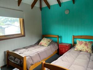 twee bedden in een kamer met groene muren en een raam bij LA BOINA DE RODRIGUEZ in San Martín de los Andes