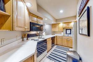 a kitchen with wooden cabinets and white counter tops at Solitude Village H103 in Ludlow