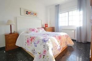 1 Schlafzimmer mit einem Bett mit Blumenbettdecke und einem Fenster in der Unterkunft Dúplex da Pedra e da Auga in Meis