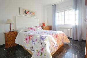 a bedroom with a bed with a floral bedspread and a window at Dúplex da Pedra e da Auga in Meis