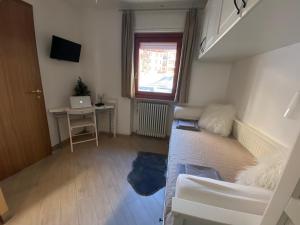 une petite pièce avec un lit, un bureau et une fenêtre dans l'établissement Casa Genepy - monolocale in centro a Sestriere, à Sestrières
