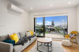 a living room with a couch and a table at Coastal Paradise - Orewa Holiday Home in Orewa