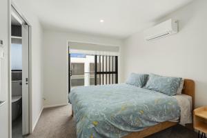 a bedroom with a bed with a blue comforter at Coastal Paradise - Orewa Holiday Home in Orewa