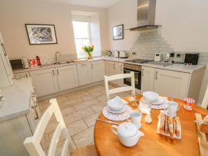 a kitchen with a wooden table with dishes on it at East Farmhouse Cottage in Humshaugh