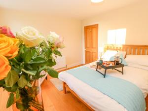 a bedroom with a bed and a vase of flowers at East Farmhouse Cottage in Humshaugh
