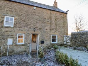an old stone house with a white door at East Farmhouse Cottage in Humshaugh