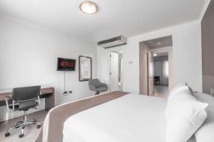 Apart Hotel Elite Las Condes في سانتياغو: غرفة نوم بسرير ومكتب وكرسي