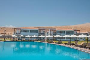 a pool with chairs and umbrellas in front of a hotel at DM Hoteles Asia in Asia