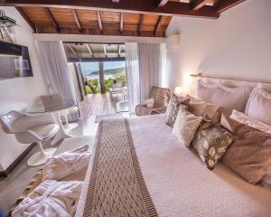 a bedroom with a large bed and a living room at Pousada Morada dos Bougainvilles in Praia do Rosa