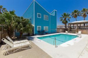 a swimming pool with lounge chairs and a blue house at Corpus Christi-Padre Island condo is walking distance to beach by Mustang Island, Sleeps Four, 2024 Traveler Award in Padre Island