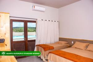 a bedroom with two beds and a balcony at Pousada Rural Estação Verde in Bonito