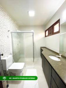 a bathroom with a toilet and a glass shower at Pousada Rural Estação Verde in Bonito