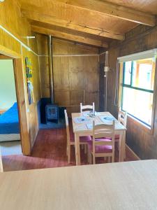 a dining room with a table and chairs and a bed at Cabañas Vista al Paine in Torres del Paine