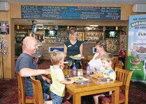 un grupo de personas sentadas en una mesa en un restaurante en Ladys Mile Holiday Park, en Dawlish