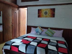 1 dormitorio con 1 cama grande y colcha colorida en Hostal La Catolica, en Quito