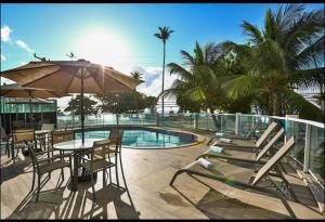 a patio with a table and chairs and a pool at Quarto em condomínio beira-mar in Recife