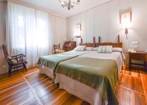 a bedroom with a large bed and a chandelier at Hotel Alcazar Irun in Irún