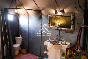 a bathroom with a sink and a mirror and a toilet at Sahara Desert Camping Merzouga & Erg Chebbi Dunes in Erfoud