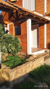 Casa de ladrillo con porche y puerta blanca en Cabañas Los Cerezos en Mina Clavero