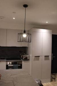 une cuisine avec des placards blancs et une lampe pendant dans l'établissement Amazing Luxury One Bedroom Apartment in the heart of Preston, à Preston