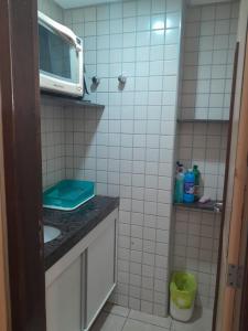 baño pequeño con fregadero y microondas en Quarto em condomínio beira-mar en Recife