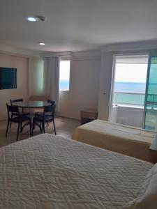 Habitación de hotel con 2 camas, mesa y sillas en Quarto em condomínio beira-mar en Recife
