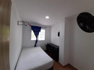 ein kleines Schlafzimmer mit einem Bett und einem Fenster in der Unterkunft MY CASA BLANCA JF in Galapa