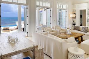 a living room with white furniture and a view of the ocean at Ambergris Cay Private Island All Inclusive in Big Ambergris Cay