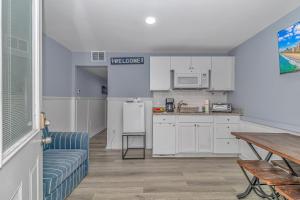 a kitchen with white cabinets and a table and a couch at 125 Atlantic Avenue Unit D - Pet Friendly! Walk To the Beach and Pier! 1BR -1BA - Sleeps 2-4 guests! in Myrtle Beach