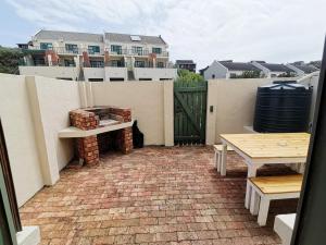 a patio with a table and a bench and a fence at Beachfront apartment in a secure complex in Port Alfred