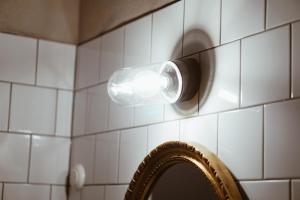 a light on a tiled wall next to a mirror at Axatorpsgården in Trelleborg